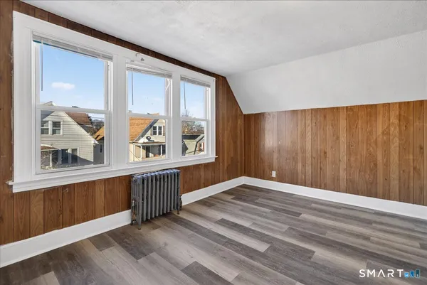 a view of an empty room with window and wooden floor