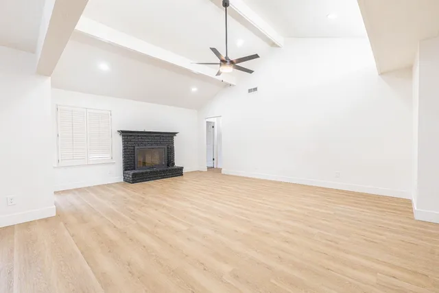 an empty room with fireplace and a ceiling fan
