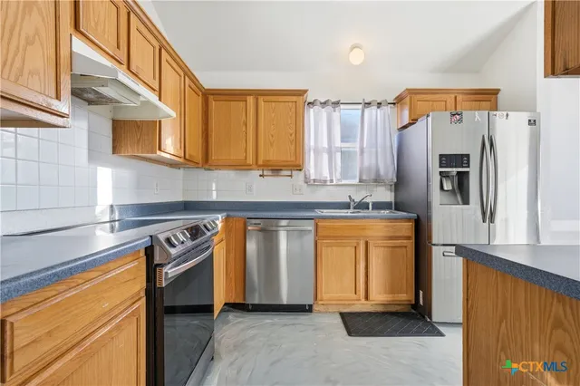 a kitchen with stainless steel appliances granite countertop a refrigerator and a stove