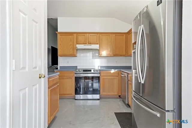 a kitchen with stainless steel appliances granite countertop a refrigerator and a stove
