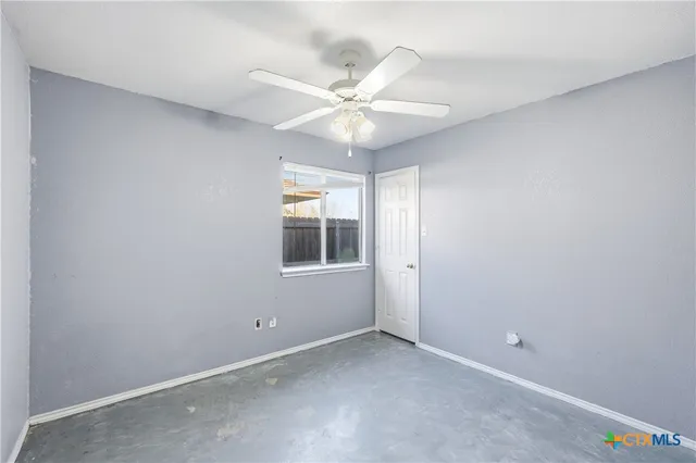 an empty room with a window and a fan