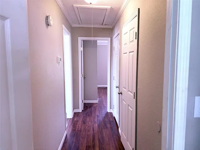 a view of a hallway with wooden floor and a bathroom