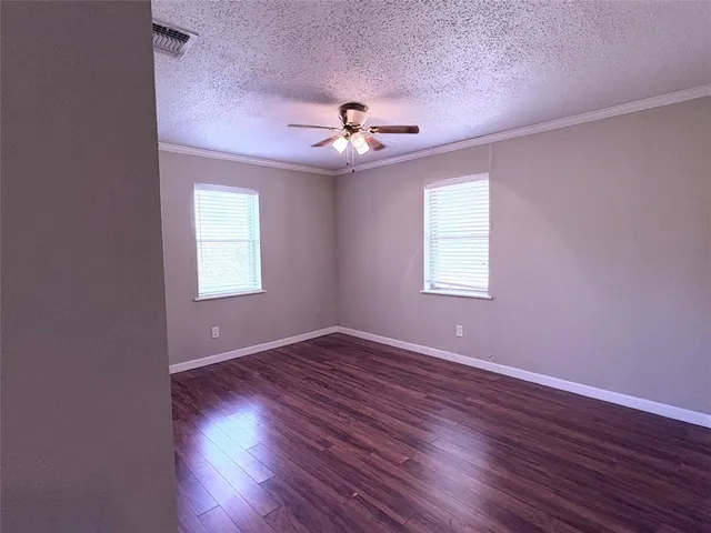 an empty room with wooden floor ceiling fan and windows