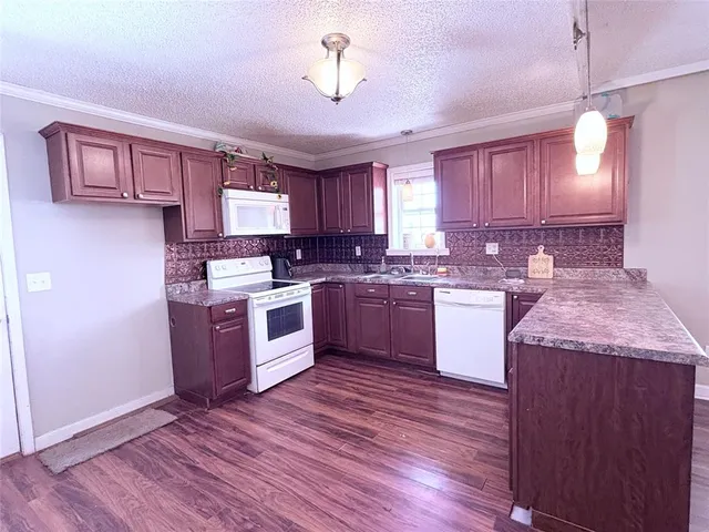a kitchen with granite countertop wooden floors stainless steel appliances a sink and a window