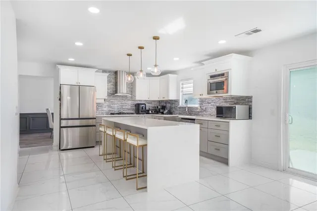 a kitchen with kitchen island a counter top space appliances and cabinets