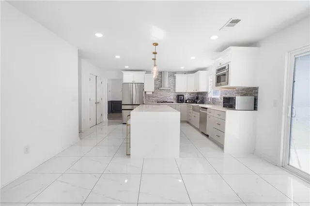 a large kitchen with granite countertop a large counter top stainless steel appliances and cabinets