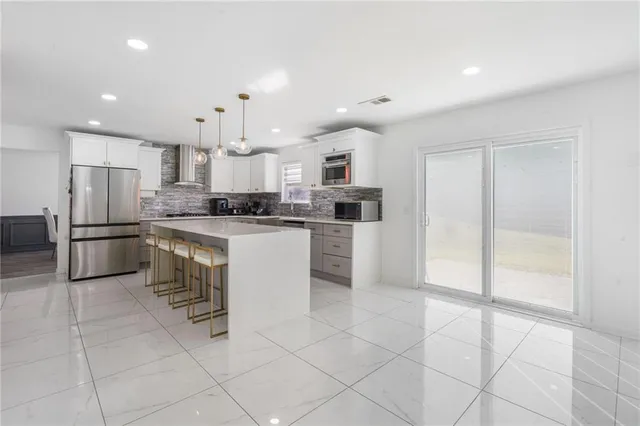 a kitchen with granite countertop a refrigerator and a stove top oven
