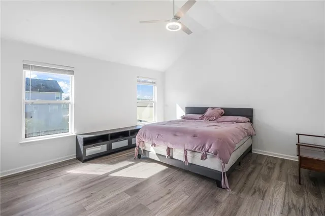 a spacious bedroom with a bed a dresser and wooden floor