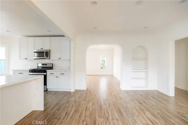 a kitchen with granite countertop a stove top oven a sink dishwasher and a refrigerator with wooden floor