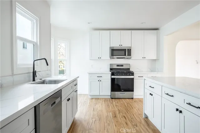 a kitchen with granite countertop a sink stainless steel appliances and white cabinets