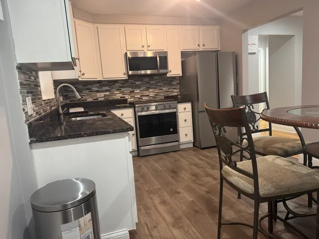 a kitchen with stainless steel appliances a refrigerator a stove a sink and white cabinets