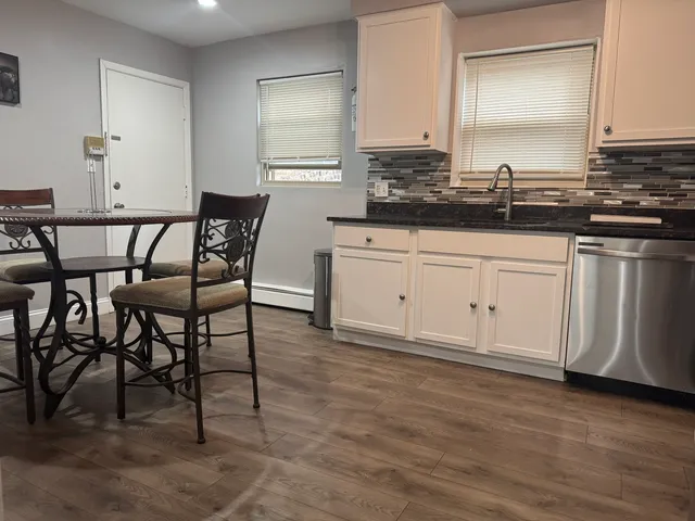 a kitchen with stainless steel appliances granite countertop a table chairs sink and cabinets