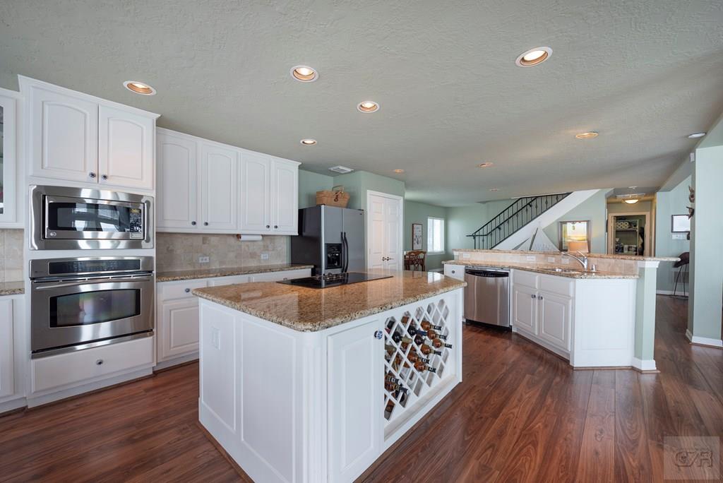 131 Isles End Road Tiki Island, TX 77554 - Photo 13 of 48 a kitchen with stainless steel appliances granite countertop a sink a stove and a wooden floors