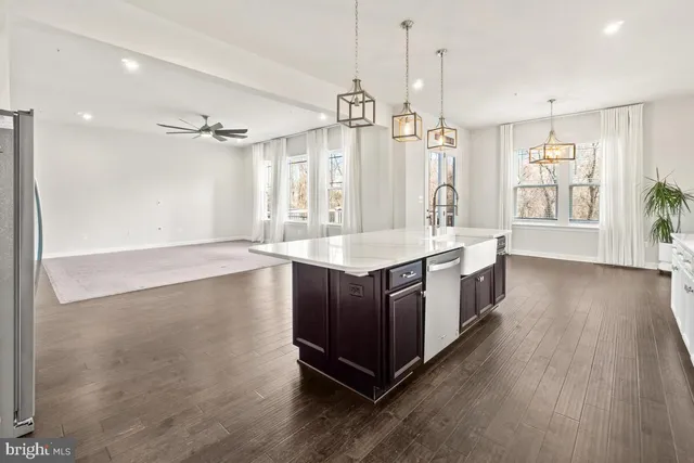 a kitchen with stainless steel appliances kitchen island granite countertop a sink a stove a refrigerator and island with wooden floor