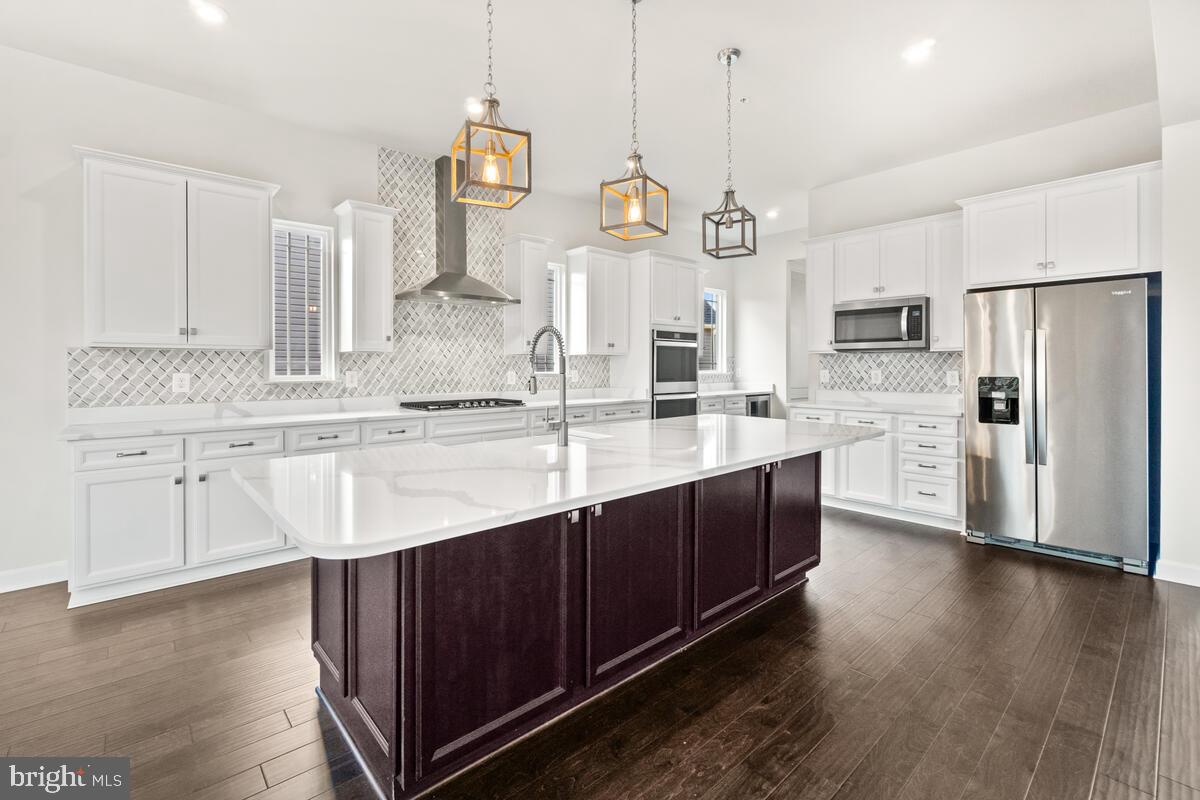 5521 Hawk Ridge Road Frederick, MD 21704 - Photo 14 of 66 a kitchen with stainless steel appliances kitchen island granite countertop a sink a stove a refrigerator and island with wooden floor