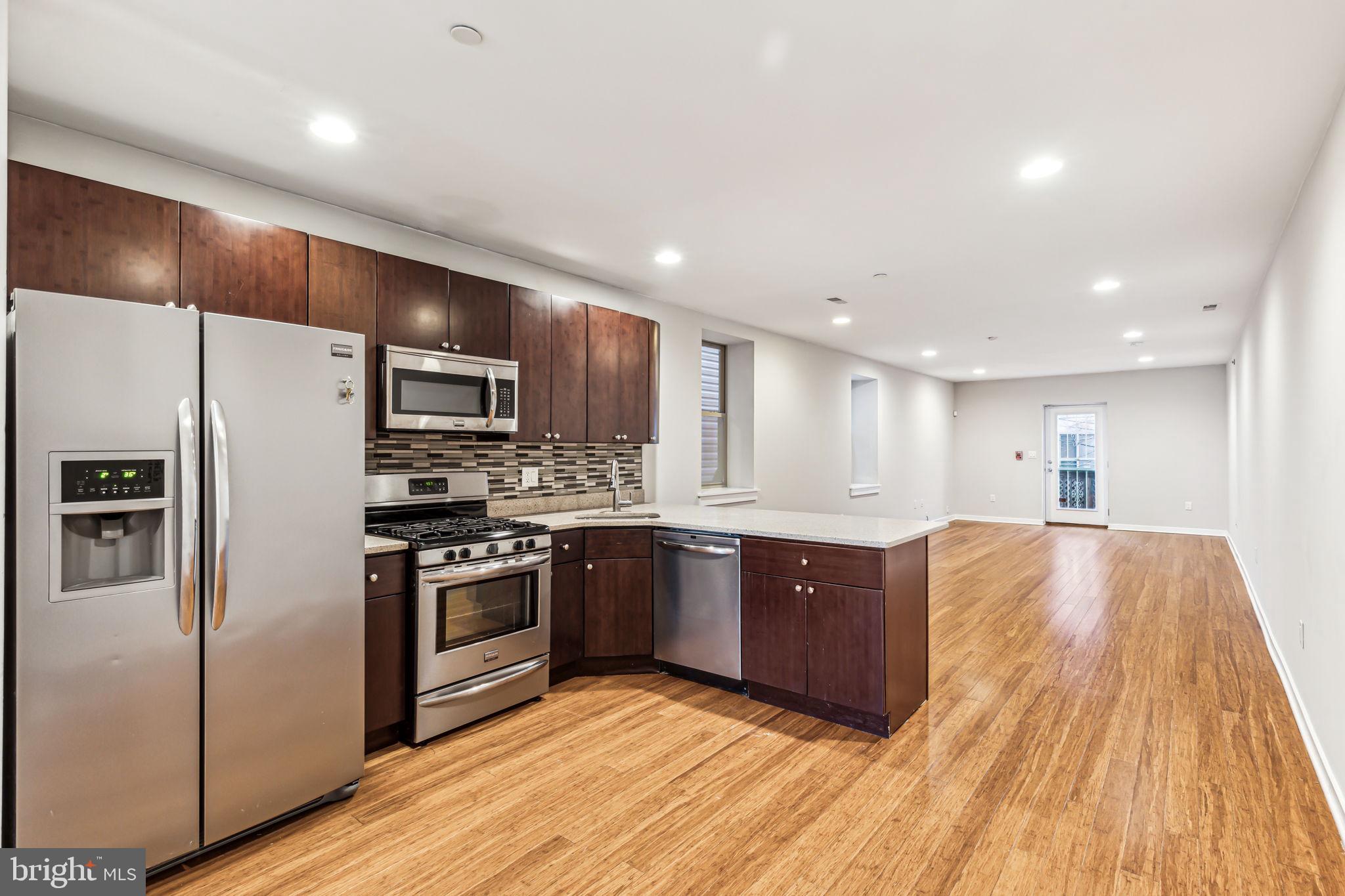 1418 Christian Street, Unit 1 Philadelphia, PA 19146 - Photo 2 of 28 a kitchen with stainless steel appliances granite countertop a refrigerator a stove top oven a sink and dishwasher with wooden floor
