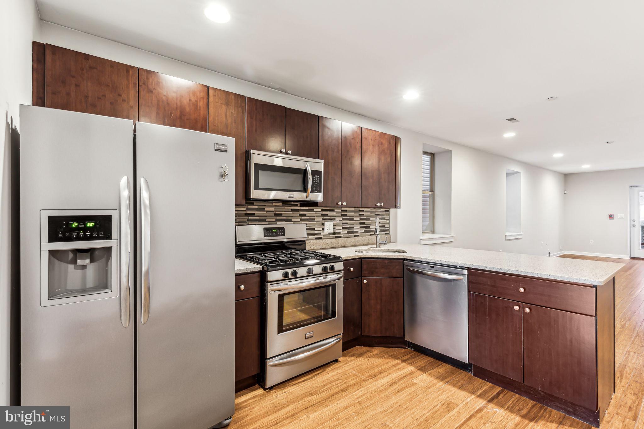 1418 Christian Street, Unit 1 Philadelphia, PA 19146 - Photo 3 of 28 a kitchen with stainless steel appliances granite countertop a refrigerator a stove top oven a sink and dishwasher