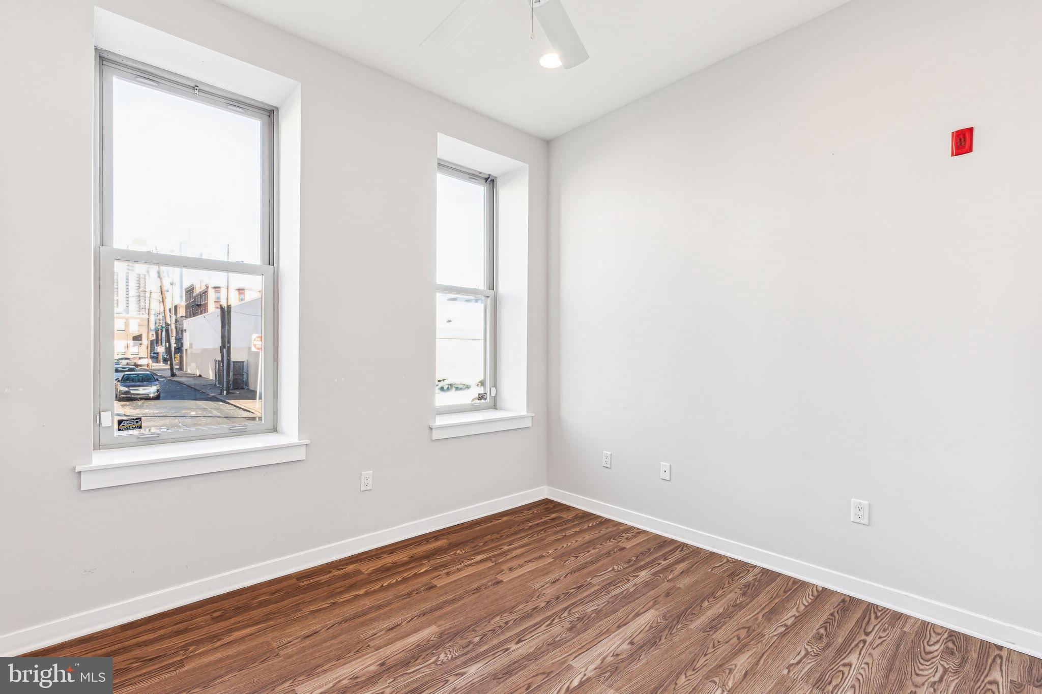 1418 Christian Street, Unit 1 Philadelphia, PA 19146 - Photo 9 of 28 an empty room with wooden floor and windows