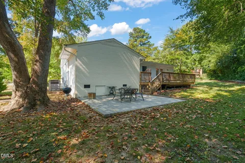 a view of a backyard with table and chairs plants and large trees
