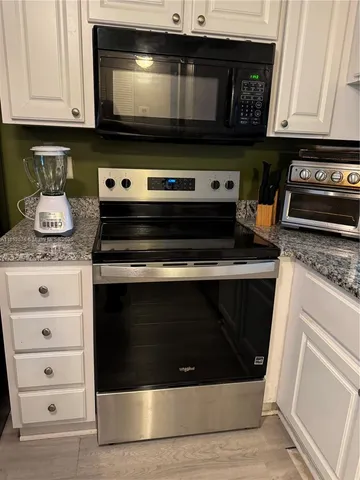 a kitchen with stainless steel appliances granite countertop a refrigerator stove a sink and a microwave