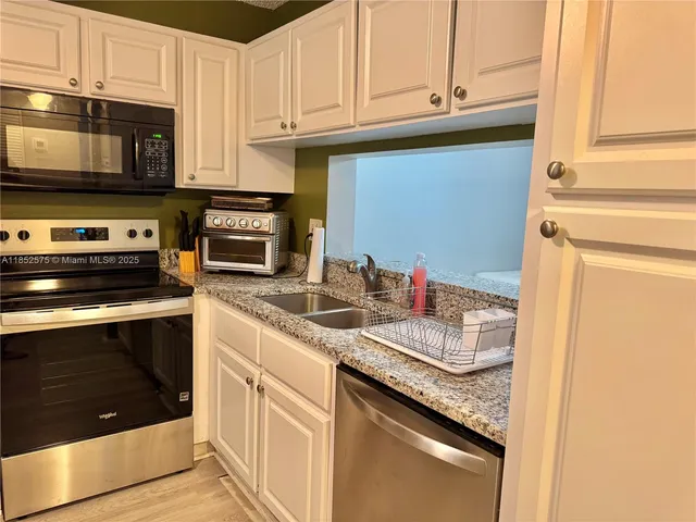 a view of a room with a hanging light and kitchen view