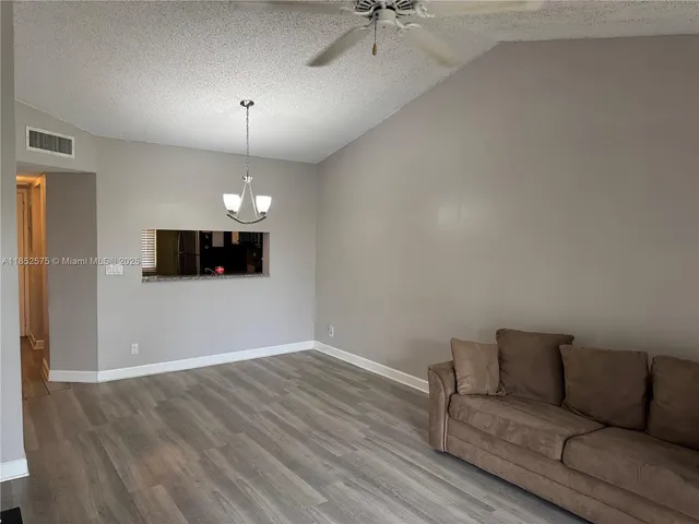 a living room with couch chandelier and a window