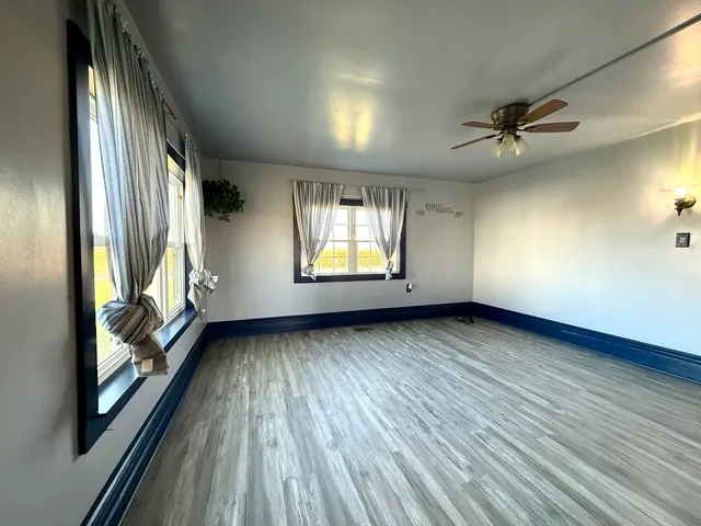 an empty room with wooden floor and windows