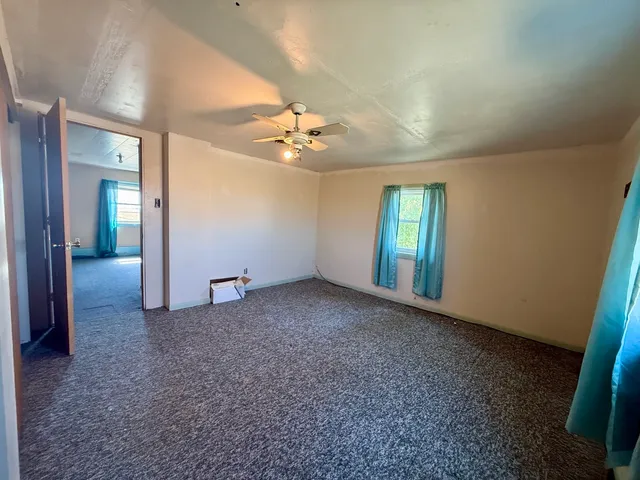 an empty room with windows and fan