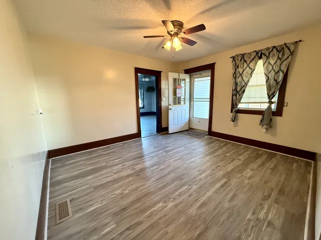 a view of an empty room with a window and wooden floor