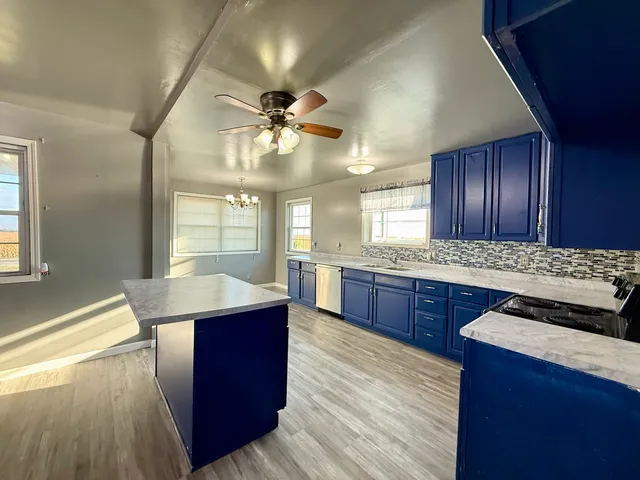 a kitchen with stainless steel appliances granite countertop wooden cabinets a stove a sink and a large window