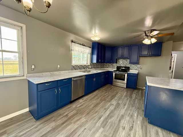 a kitchen with stainless steel appliances granite countertop wooden cabinets a stove a sink and a window