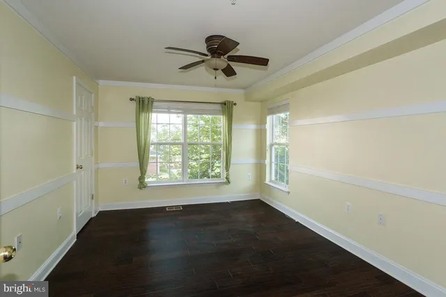 an empty room with wooden floor fan and windows