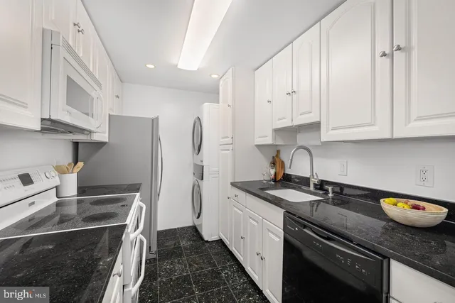 a kitchen with granite countertop a sink a stove and cabinets