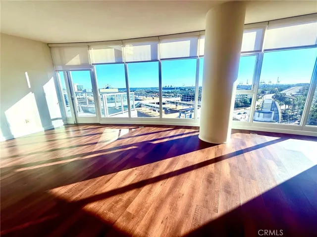 a view of an empty room with wooden floor and a floor to ceiling window