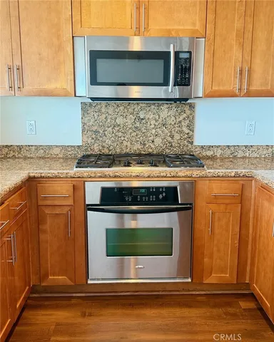 a kitchen with stainless steel appliances wooden cabinets and a stove top oven