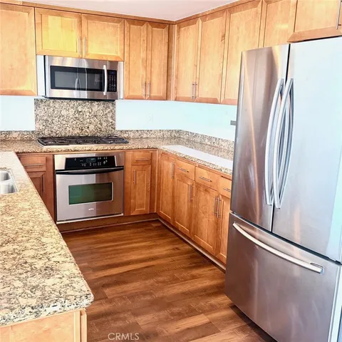 a kitchen with stainless steel appliances granite countertop a refrigerator a stove and a sink with large window