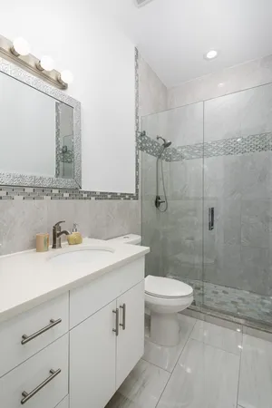 a bathroom with a granite countertop sink mirror vanity and toilet