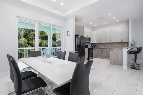 a kitchen with stainless steel appliances kitchen island granite countertop a table chairs and a refrigerator