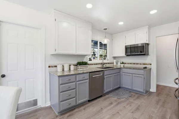 a kitchen with stainless steel appliances granite countertop a stove a sink dishwasher a refrigerator and a microwave oven with wooden floor