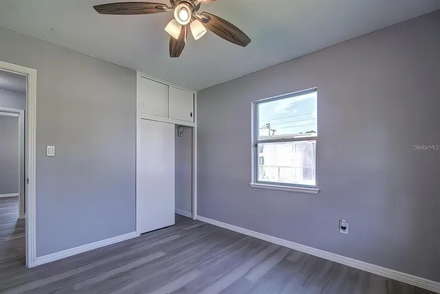 a view of an empty room with wooden floor and a window