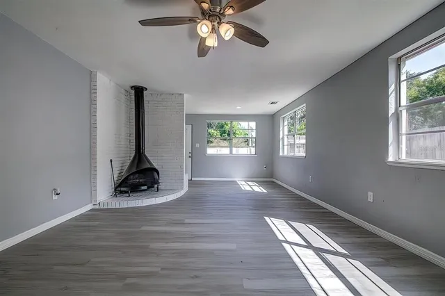 a view of an empty room with window and wooden floor