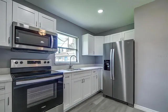 a kitchen with stainless steel appliances a stove microwave and sink