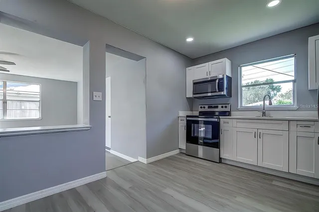a kitchen with granite countertop a refrigerator and a stove top oven