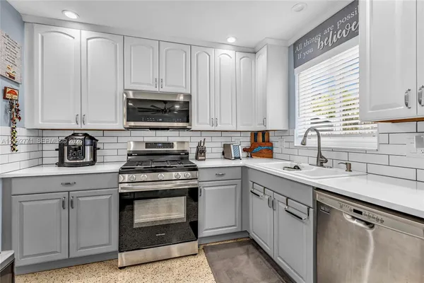 a kitchen with cabinets appliances a sink and a window