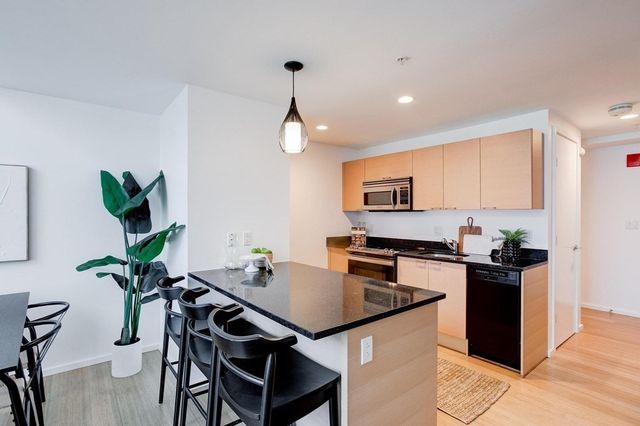 a kitchen with stainless steel appliances granite countertop a stove top oven a sink a dining table and chairs with wooden floor