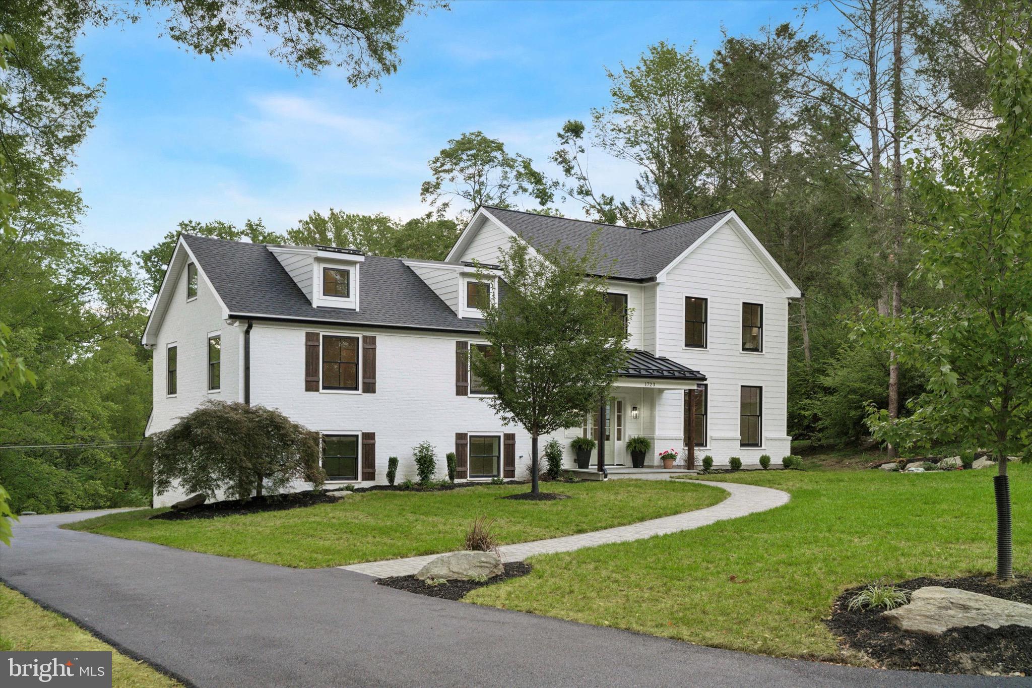 a view of a white house with a big yard plants and large trees