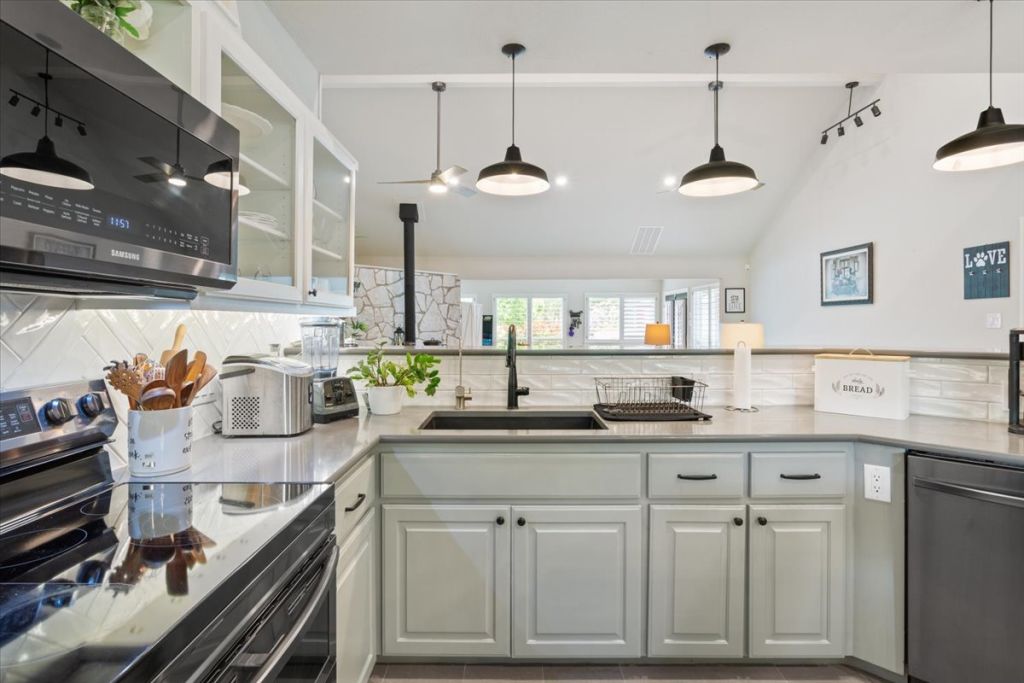 190 Young Ranch Road Georgetown, TX 78633 - Photo 11 of 40 Kitchen featuring stainless steel appliances, tasteful backsplash, white cabinets, glass insert cabinets, and light stone countertops