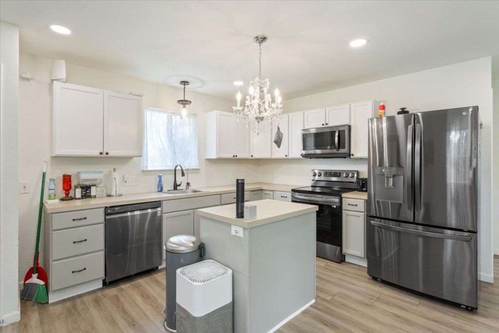 190 Young Ranch Road Georgetown, TX 78633 - Photo 21 of 40 Kitchen featuring stainless steel appliances, light countertops, light wood finished floors, and white cabinets