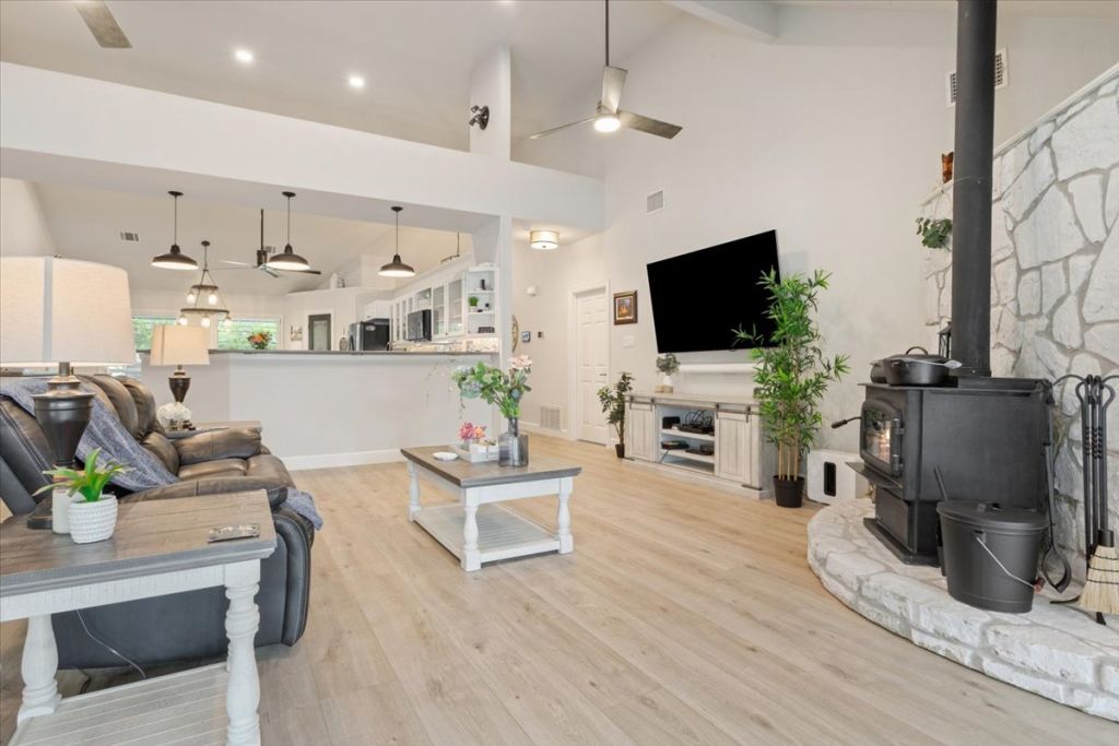 190 Young Ranch Road Georgetown, TX 78633 - Photo 7 of 40 Living room featuring ceiling fan, light wood-style flooring, lofted ceiling, and a wood stove