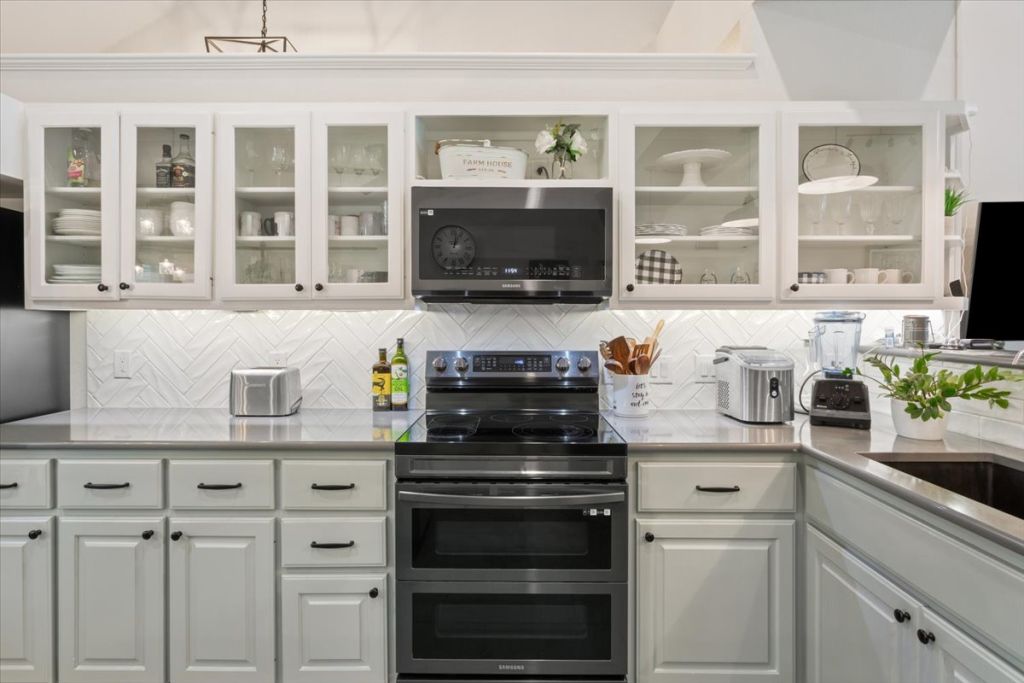 190 Young Ranch Road Georgetown, TX 78633 - Photo 10 of 40 Kitchen featuring stainless steel appliances, white cabinets, light stone counters, and tasteful backsplash